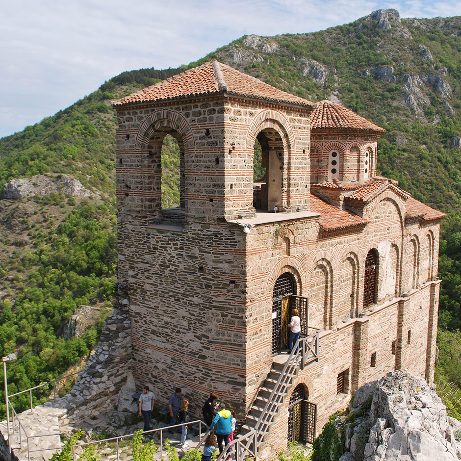 Tourists climbing stone steps to explore the impressive interior of Asen’s Fortress church in Bulgaria