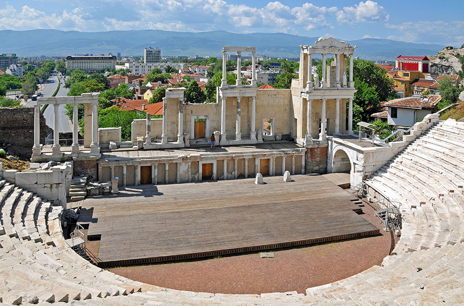 Plovdiv Roman theatre as seen from one of the top steps with views of mountains and modern buildings in the background